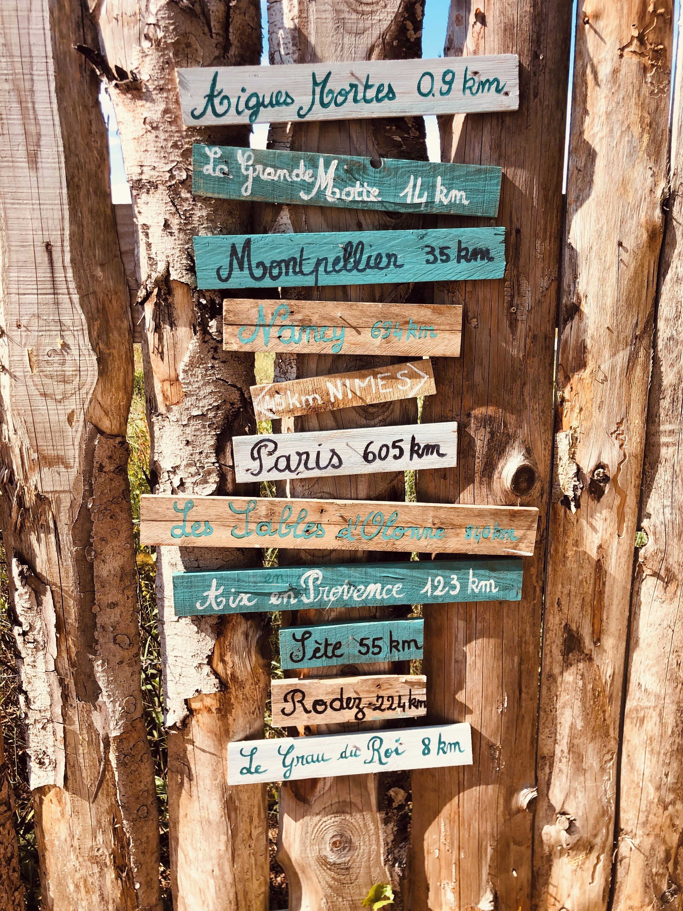 A wooden signpost with distance markers to various destinations.