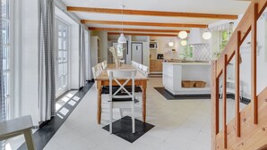 A spacious kitchen with wooden beams, a dining area with a table and chairs, and a view of the adjacent living area. - "Sirkku" - 320m from the sea by Interhome (Tranekær)