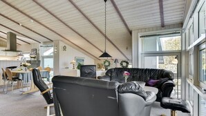 A spacious living area with a black leather sofa, a dining table with chairs, and a kitchen visible through an open door. - "Roel" - 500m from the sea by Interhome (Tranekær)