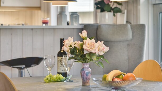 A dining table with a vase of flowers, a bowl of fruit, and wine glasses. - "Roel" - 500m from the sea by Interhome (Tranekær)