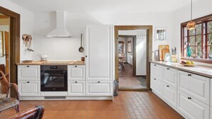 A kitchen with white cabinets, a stove, and a dining area with a chair. - "Elvin" - 2.7km from the sea by Interhome (Humble)