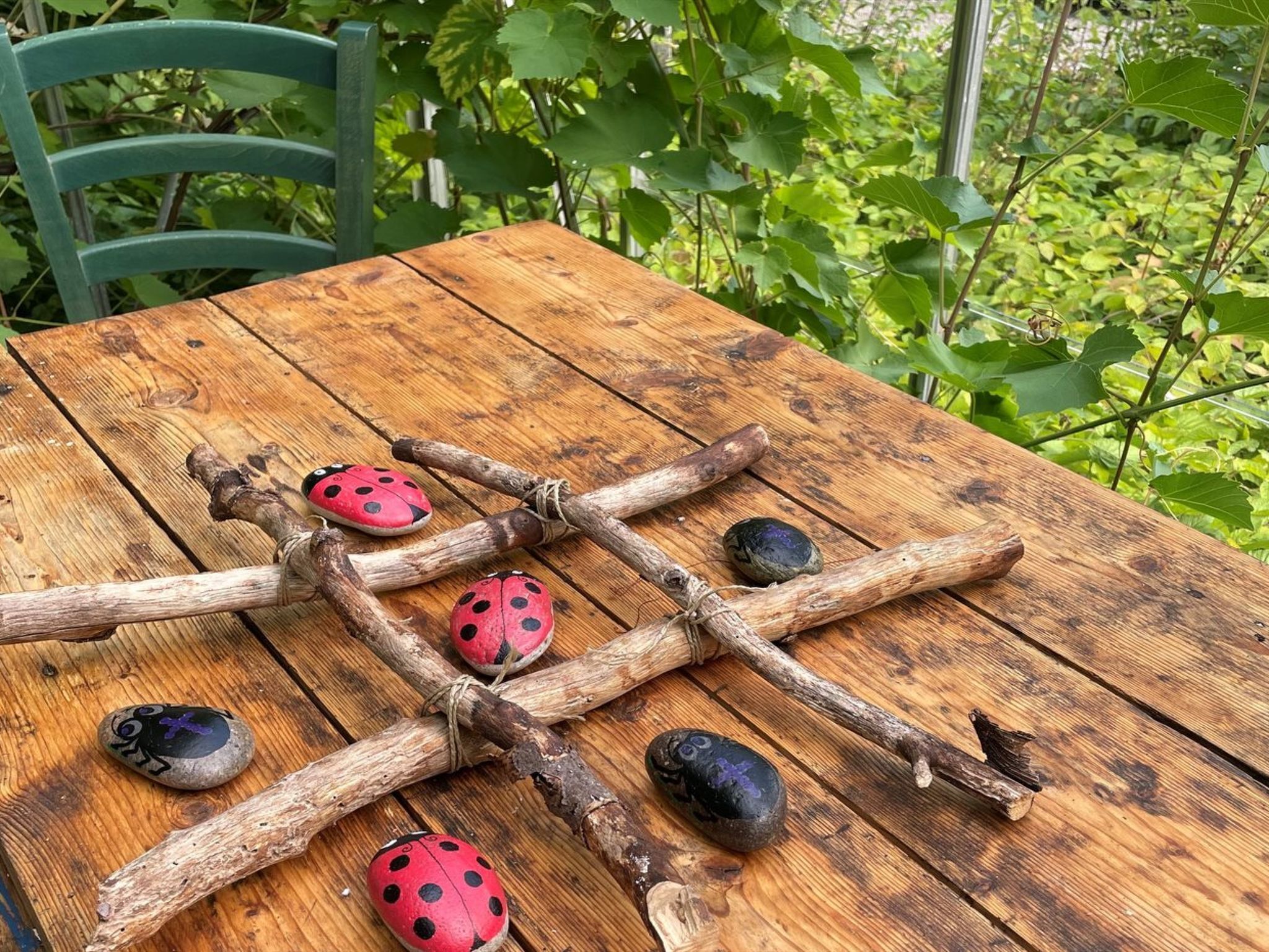 A rustic wooden table with a lattice structure made of branches and painted ladybug decorations.
