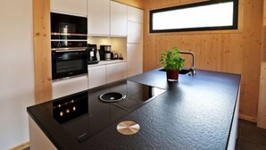 Een moderne keuken met een zwart inductiefornuis, witte kasten en een raam boven de gootsteen.