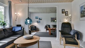 A modern living room with a sofa, a coffee table, and a dining area with a table and chairs.