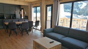 A modern living room with a sofa, a coffee table, and a dining area with chairs and a table.