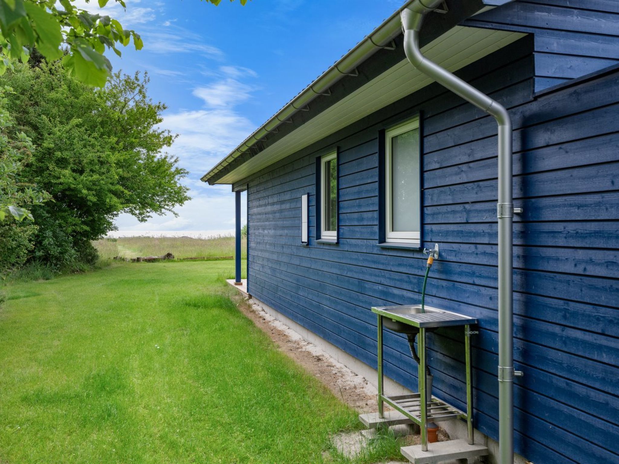 Una casa azul con una pequeña mesa exterior y una manguera.