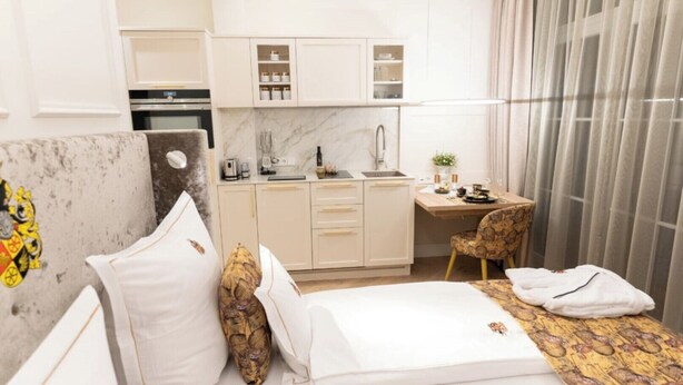 Ein kleines Hotelzimmer mit Bett, Schreibtisch und Kochnische.