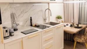 Eine moderne Küche mit Marmorarbeitsplatte, Spüle und einem Essbereich mit Tisch und Stuhl.