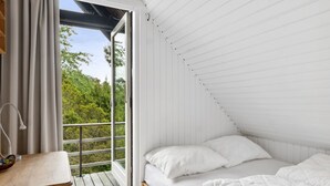 A bedroom with a bed, a wooden desk, and a view of greenery through a sliding door. - "Wiger" - 150m from the sea by Interhome (Humble)