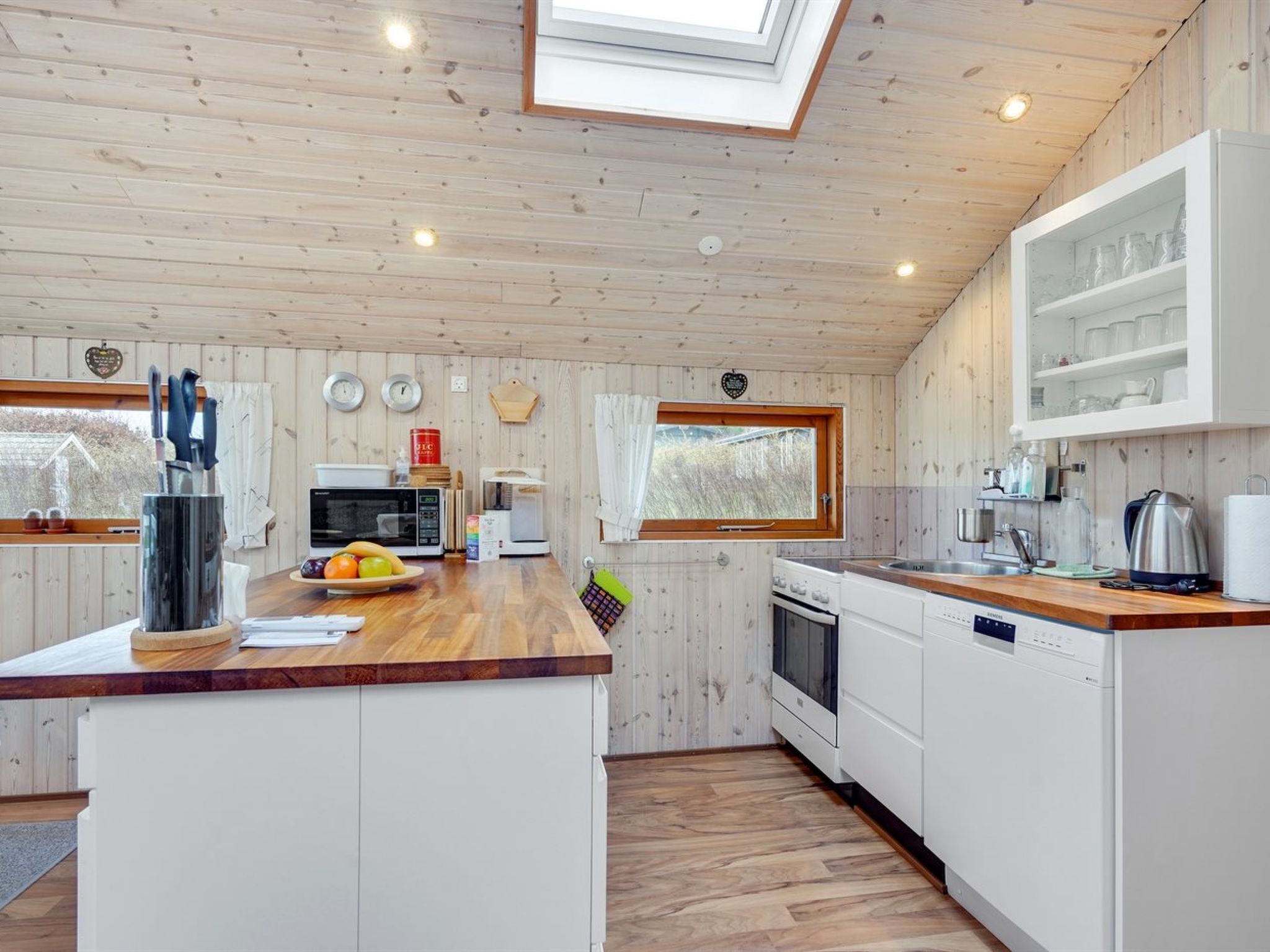 Une cuisine moderne avec des murs en bois, un îlot central et des appareils électroménagers intégrés.