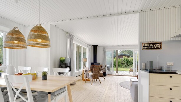 Una cocina moderna con comedor, ventanas amplias y un cartel que dice "FOOD IS GOOD WINE IS BETTER".