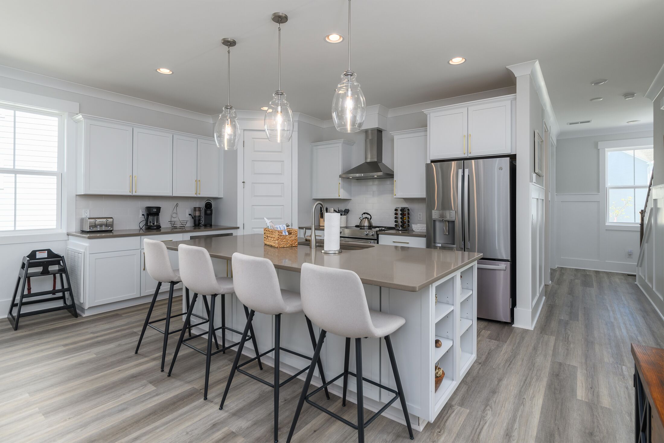 A modern kitchen with white cabinets, stainless steel appliances, and a central island with bar stools.