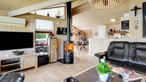 Interior moderno de cabaña con chimenea, asientos de cuero, televisor de pantalla plana y comedor.