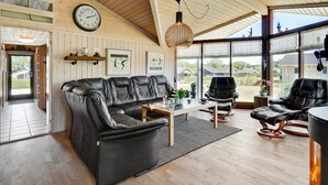 Un salón amplio con un sofá de cuero negro, una mesa de centro de madera y un ventanal con vistas al exterior.