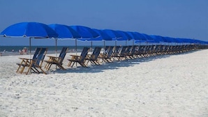 A beach with rows of blue umbrellas and wooden lounge chairs. - 69 Heated Pool | Kids Retreat | Near Beach | Sleeps Big (Hilton Head Island)