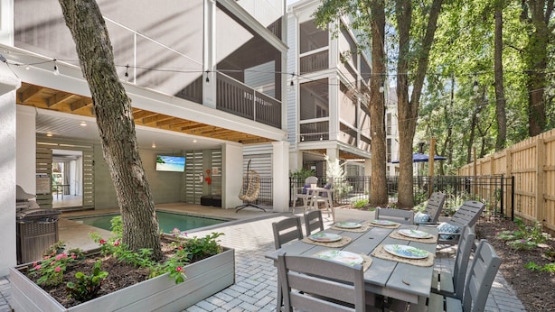 An outdoor patio with a pool, wooden deck, and a dining area with tables and chairs. - 69 Heated Pool | Kids Retreat | Near Beach | Sleeps Big (Hilton Head Island)