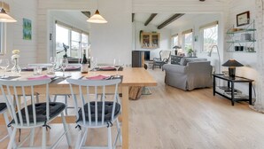 A spacious dining area with a wooden table set for a meal, surrounded by white chairs. - "Ylvie" - 150m from the sea by Interhome (Frørup)