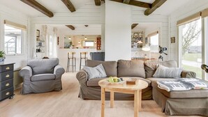 A spacious living room with a grey sofa, a brown sofa, and a wooden coffee table. There is a kitchen area in the background with bar stools and a dining table. - "Ylvie" - 150m from the sea by Interhome (Frørup)