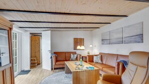 Un salon moderne avec un plafond en bois, un ensemble de canapés, une table basse et une table à manger.