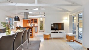 A modern living room with a dining area, a kitchen, and a TV.