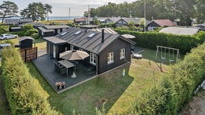 A modern house with a deck, a swing set, and a view of the sea.