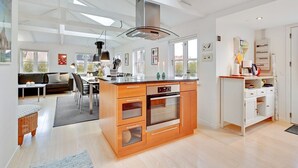 A modern kitchen with a central island, wooden cabinets, and a built-in oven.