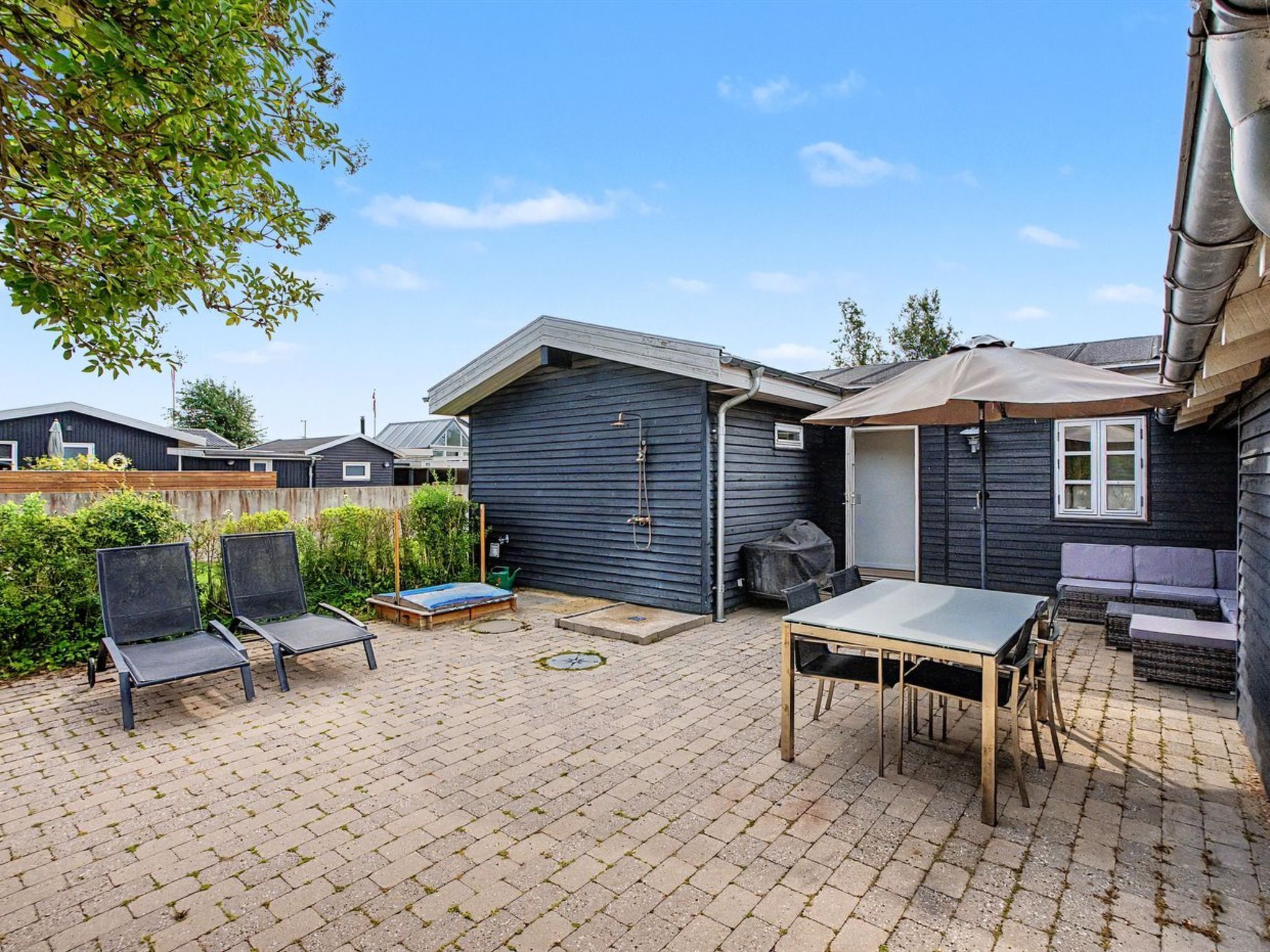 A backyard with a patio, a barbecue grill, and outdoor seating.