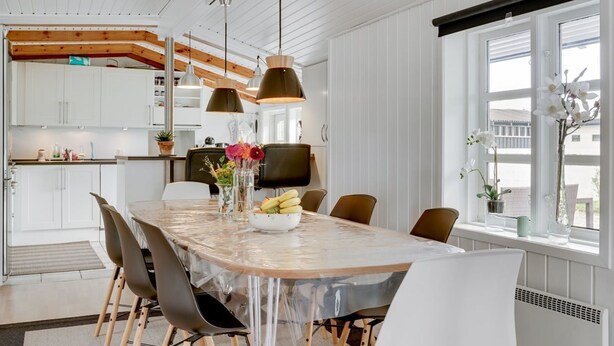 Una cocina moderna con armarios blancos, techo de madera e iluminación colgante.