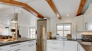 Cocina moderna con muebles blancos, refrigerador de acero inoxidable y un amplio ventanal que proporciona luz natural.