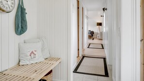 Un pasillo con un banco, un reloj y una puerta que da a otra habitación.