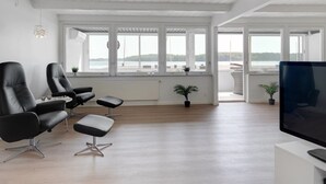 A spacious living room with a large TV, comfortable seating, large windows, and a view of the outdoors. - "Constance" - 50m from the sea by Interhome (Svendborg)