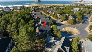 An aerial view of a coastal residential area with houses, a large rock formation, and a beach. - Beachcomber Cottage - Short Distance to Beach 2 Bedroom - 2 Bath (Pacific City)