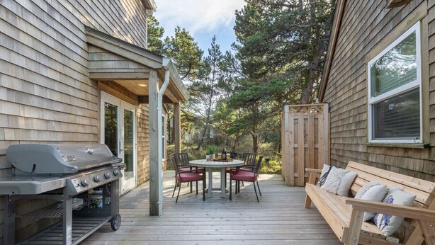 A wooden deck with a grill, a round table with chairs, and a wooden bench. - Beachcomber Cottage - Short Distance to Beach 2 Bedroom - 2 Bath (Pacific City)