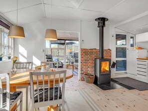Cozy room with a central fireplace, dining table, and kitchen area.