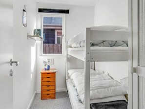Cozy bedroom with a bunk bed setup, wooden dresser, and a window with a view.