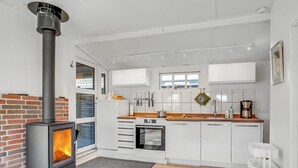 Una cucina moderna con stufa a legna, mobili bianchi e piano di lavoro in legno.