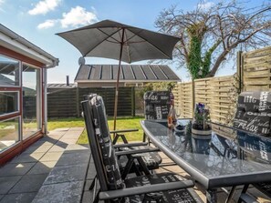 Enjoy a tranquil outdoor space with a glass-top table, comfortable seating, and a shaded area beneath an umbrella.