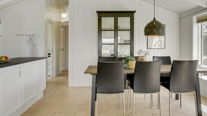 Une cuisine moderne avec des meubles blancs, un plancher en bois et un coin repas comprenant une table et des chaises.