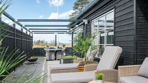 Une terrasse extérieure aménagée avec des meubles en osier, un barbecue et des plantes en pot.