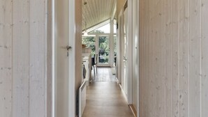 A hallway with wooden paneling, a radiator, and a view into a dining area with a table and chairs. - "Rathi" - 250m from the sea by Interhome (Haarby)