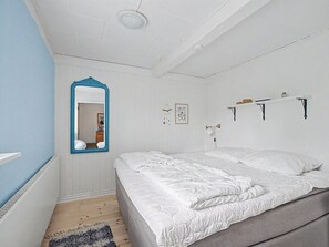 Une chambre à coucher avec un lit, un miroir, une étagère fixée au mur et un tapis à motifs.