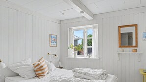 Una camera da letto con un letto, una finestra con tende, un comodino e uno specchio appeso al muro.