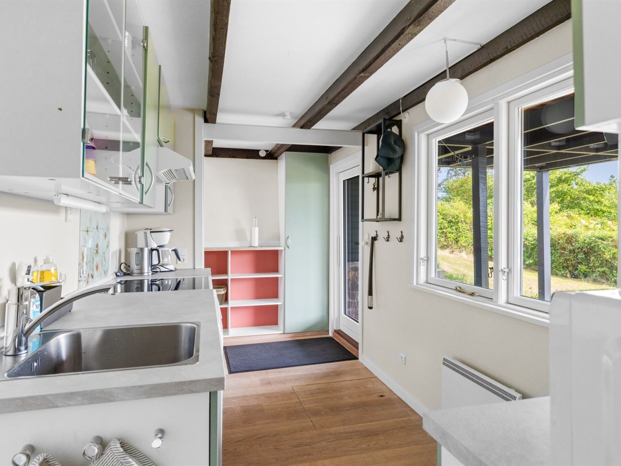 Een moderne keuken met een ingebouwde gootsteen, houten balken en een groot raam met uitzicht op een tuin.
