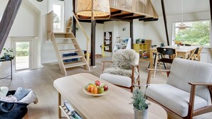 Un vaste espace de vie de style loft, doté d’un haut plafond, d’un escalier en bois, d’un coin repas et d’une grande fenêtre laissant entrer la lumière naturelle.