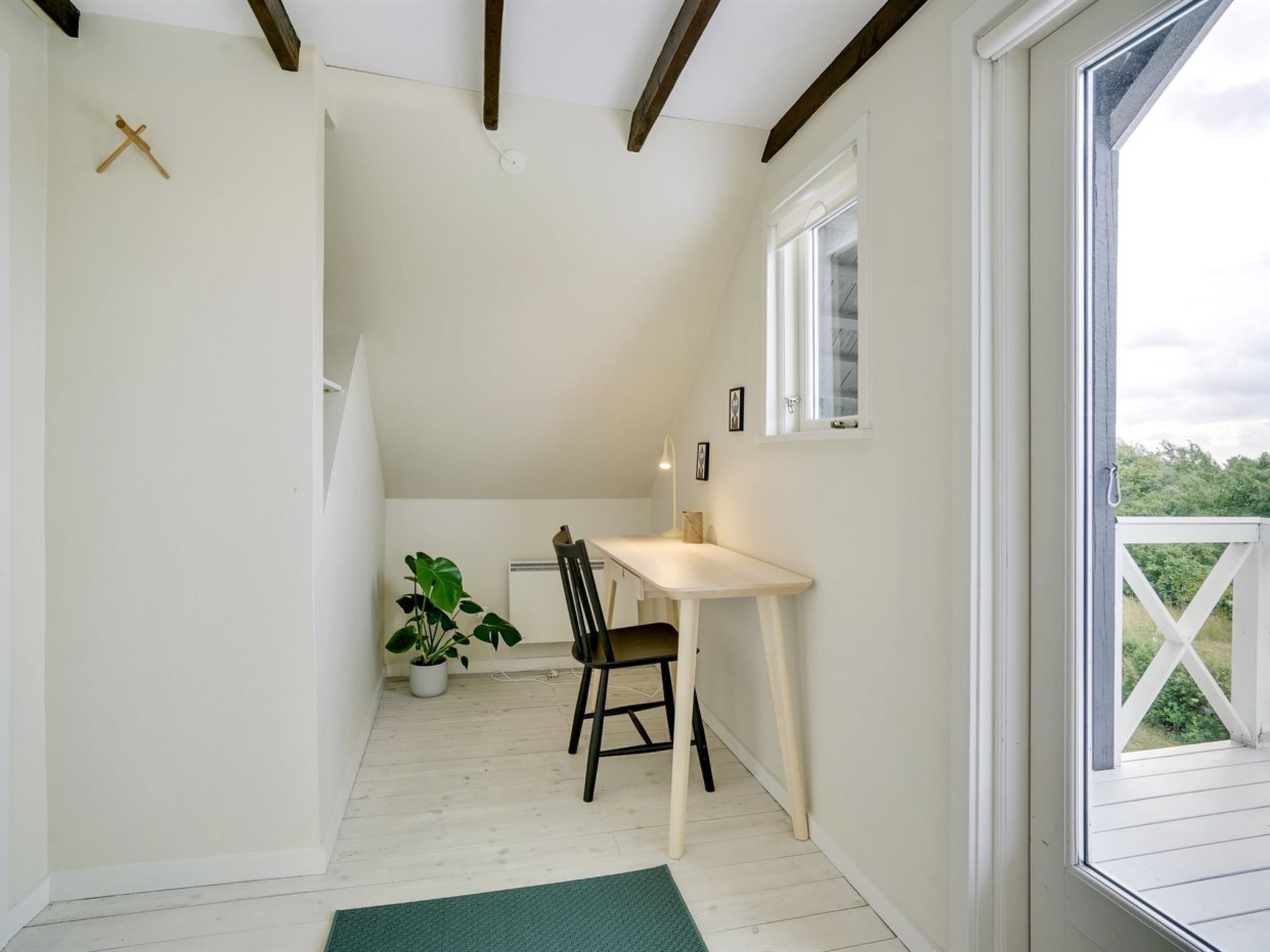 Une petite pièce bien éclairée, avec un bureau en bois, une chaise et une plante en pot.