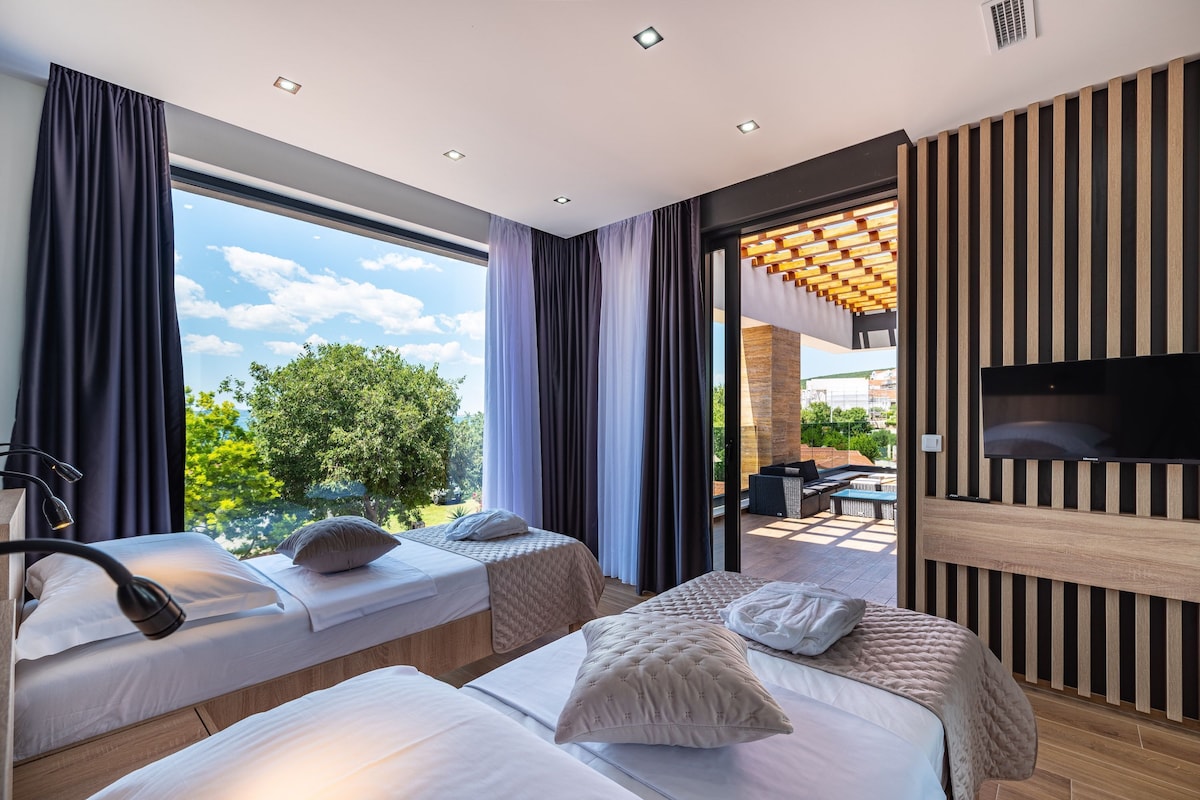 Habitación de hotel moderna con dos camas, televisión y vistas al exterior.