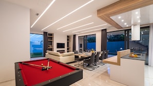 Uma sala de estar moderna com mesa de bilhar, espaço de jantar e cozinha.