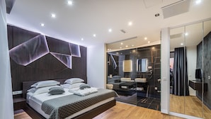 Quarto moderno com cama grande, closet espaçoso e banheiro com espelho e pia.