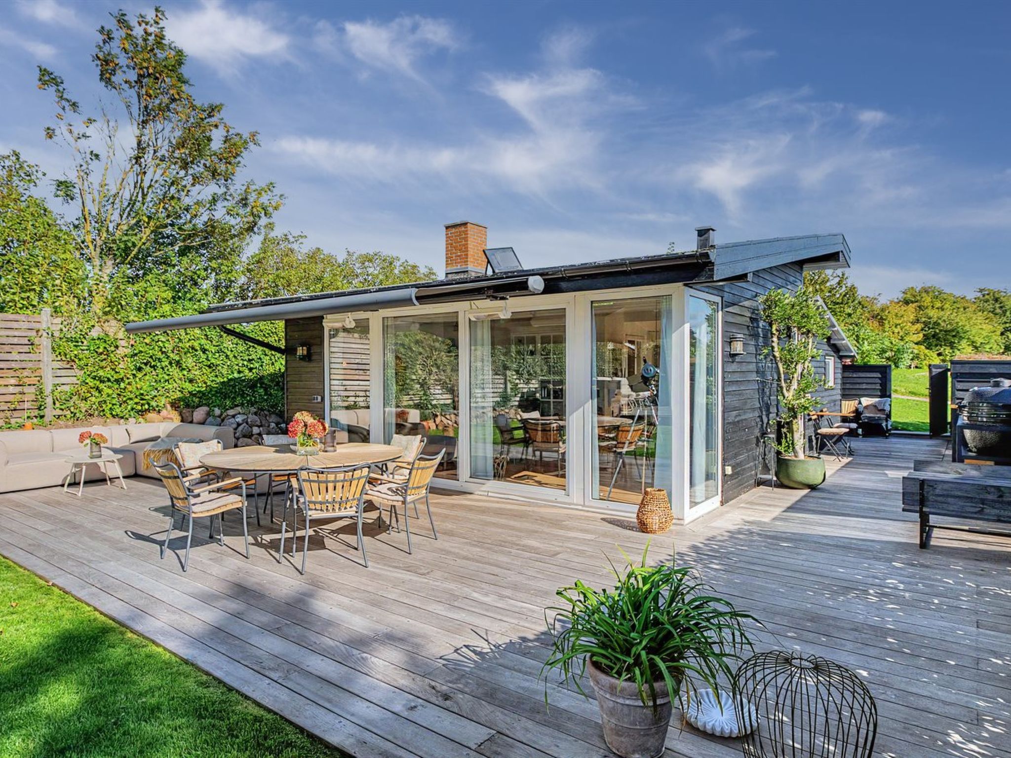 Un patio moderno al aire libre con zona de comedor, equipo de barbacoa y terraza de madera.