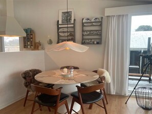 Un'area pranzo con un tavolo rotondo, due sedie, una lampada a sospensione e vista dalla finestra.